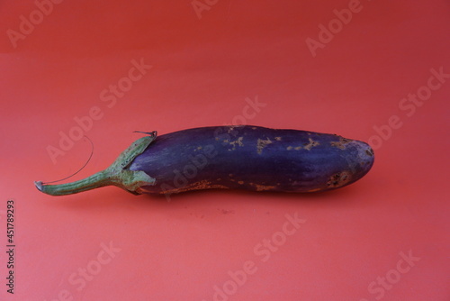 Unripe raw purple eggplant on orange background Fresh vegetables. Space for text. Top view. Natural purple whole eggplant fruit. Copy space. Suitable for vegetables, health care, nutritious food