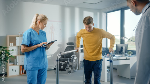 Картината върху платно Hospital Physical Therapy: Determined Male Patient with Injury Successfully Walks Holding Parallel Bars