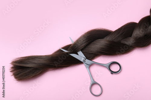 Professional hairdresser scissors and braid on pink background, flat lay. Haircut tool