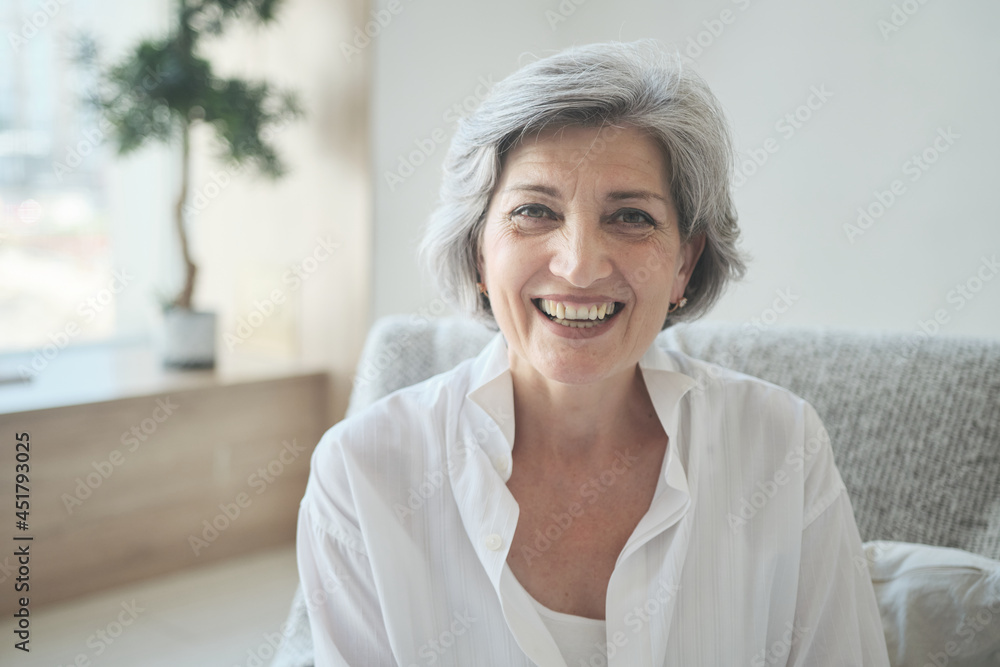 Smiling 60s older senior middle-aged adult lady using video conference calling virtual family online chat with children and grandchildren, meeting on couch at home, social distance Smiling 60s older senior middle-aged adult lady using video conference calling virtual family online chat with children and grandchildren, meeting on couch at home, social distance