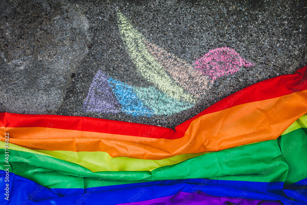dove of peace painted with chalk on the street, under it the rainbow flag