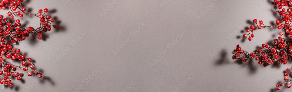 Banner of red berries on the branch Christmas decoration on gray background on the left and right side. Top view flat lay. Holidays concept with copy space Banner of red berries on the branch Christmas decoration on gray background on the left and right side. Top view flat lay. Holidays concept with copy space