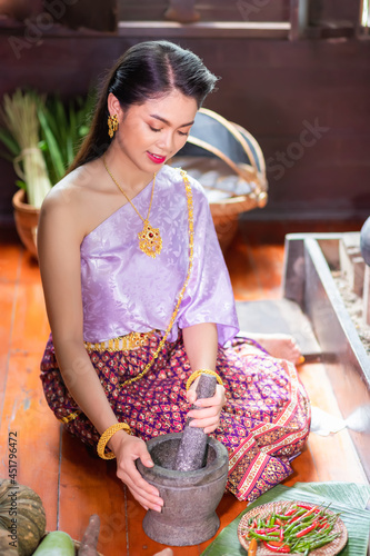 Photography Thai Asian women dressed in ancient Thai costumes from the Ayutthaya period are pounding chili paste and preparing savory dishes in a wooden household