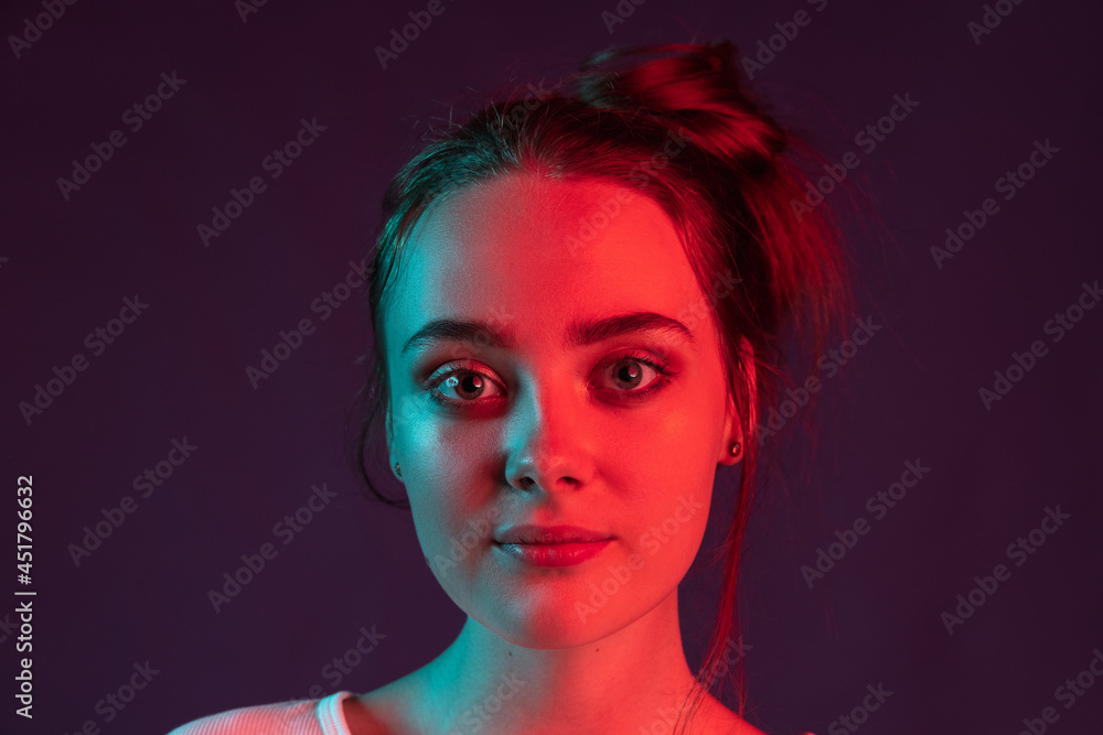 Close up face of sweet, pretty girl on dark purple studio background in red neon light, filter. Concept of human emotions, facial expression. Close up face of sweet, pretty girl on dark purple studio background in red neon light, filter. Concept of human emotions, facial expression.