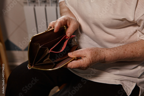 The older woman counts the money. An elderly woman Caucasian old woman gray-haired grandmother takes money out of her purse and counts it. Old hands hold bills.