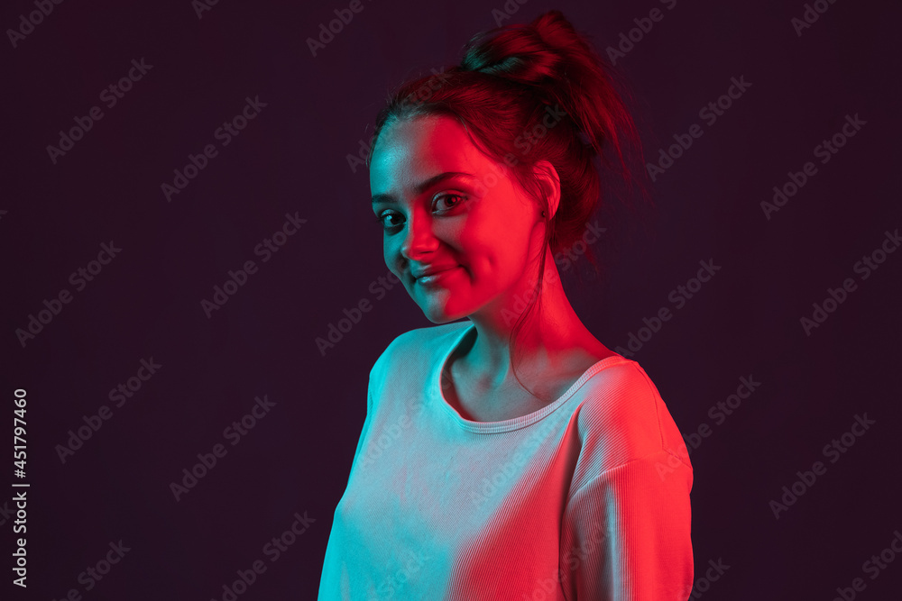 Close up portrait of sweet, pretty romantic girl on dark purple studio background in red neon light, filter. Concept of human emotions, facial expression. Close up portrait of sweet, pretty romantic girl on dark purple studio background in red neon light, filter. Concept of human emotions, facial expression.