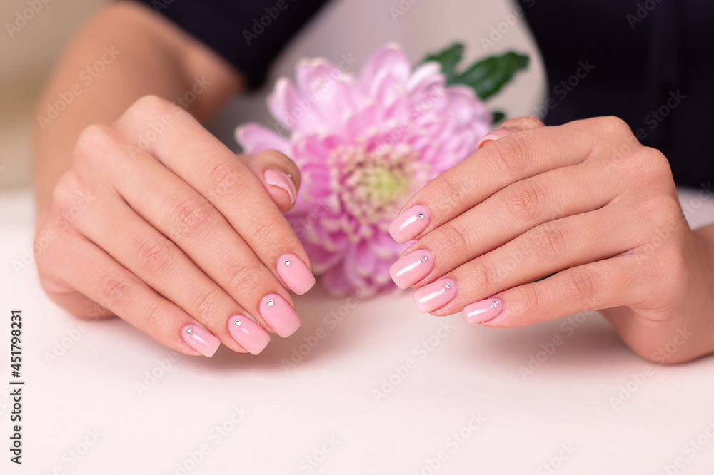 Beautiful female hands with wedding manicure nails, pink gel polish, peony flower