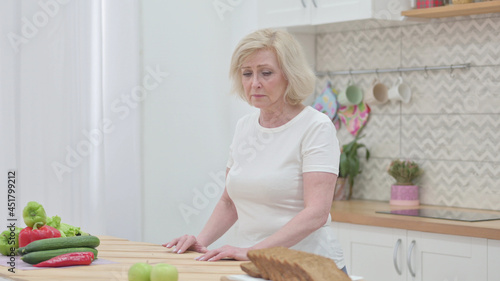 Sad Old Woman Standing in Kictchen photo