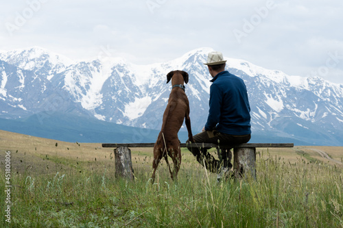 Foto A guy with a dog sits on a bench and admires the mountain scenery
