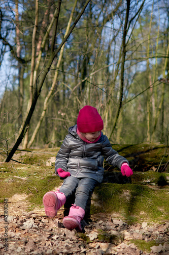 Little girl having fun in beautiful forest with dry yellow leaves and green moss