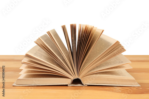 Open book on wooden table against white background. Library material