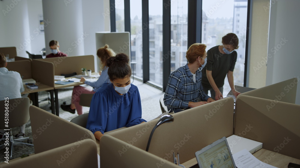 Fototapeta premium Employees in protective masks working in open space. Team busy at workplace
