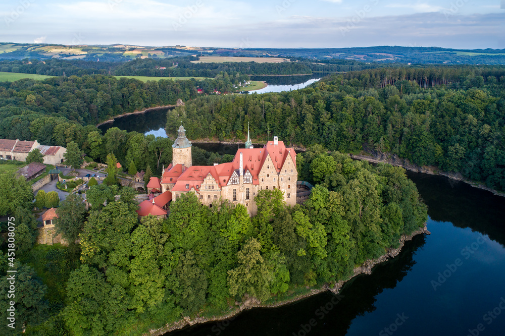 Czocha medieval castle in Lower Silesia in Poland. Built in 13th century  with many later additions. Aerial view in summer, early morning. Kwisa river with artificial lake Lesnianskie and forests