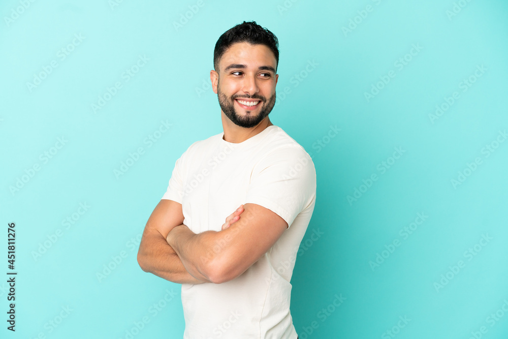 Young arab man isolated on blue background with arms crossed and happy Young arab man isolated on blue background with arms crossed and happy
