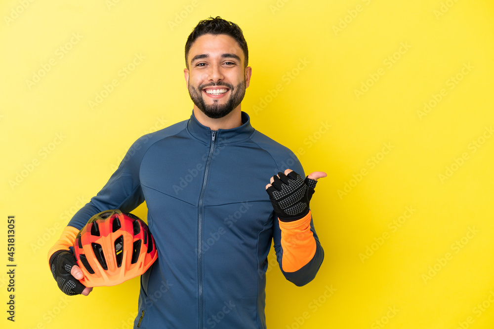 Young cyclist arab man isolated on yellow background pointing to the side to present a product
