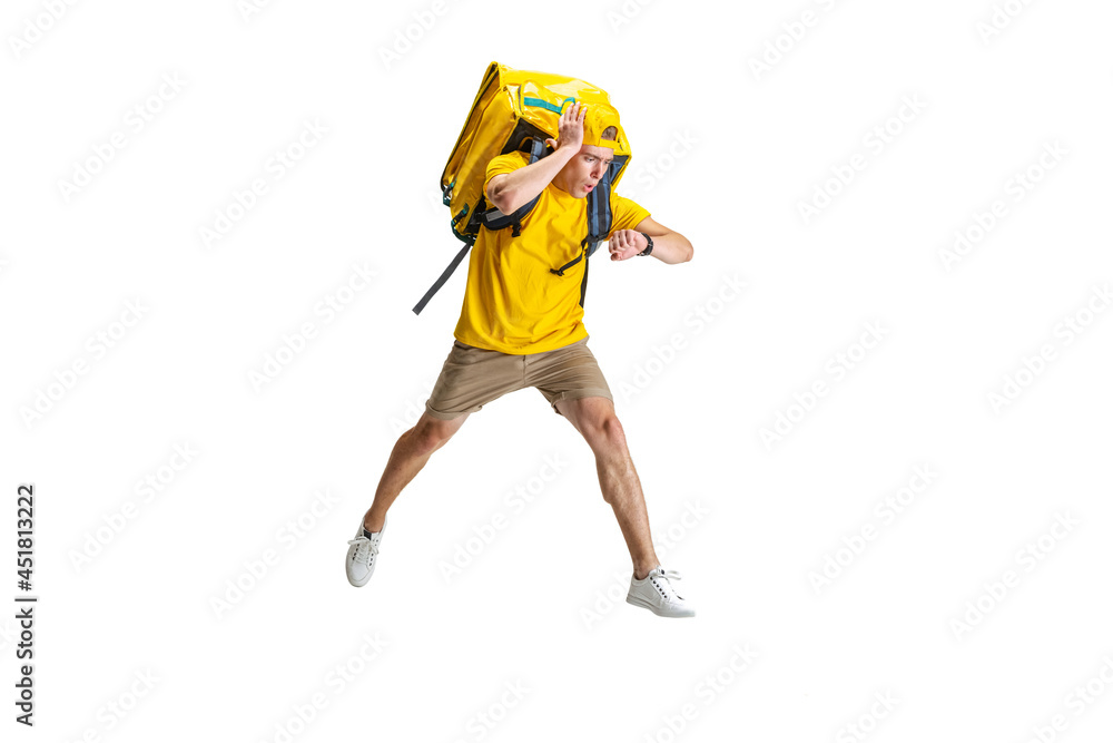 Young delivery man in yellow uniform running to deliver order isolated on white background. Concept of convenience, speed, comfort, safety, service.
