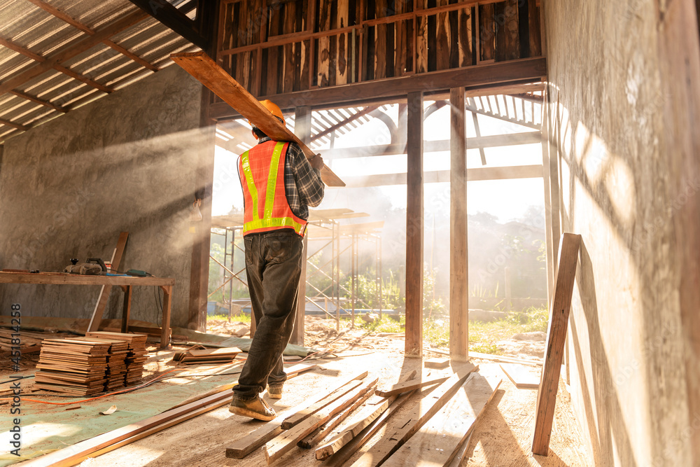Fototapeta premium Carpenter holds wooden planks on construction site