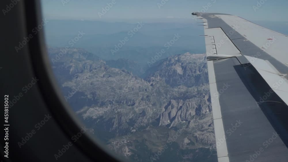 Airplane wing flies over the relief rocky, black mountains of Montenegro Airplane wing flies over the relief rocky, black mountains of Montenegro
