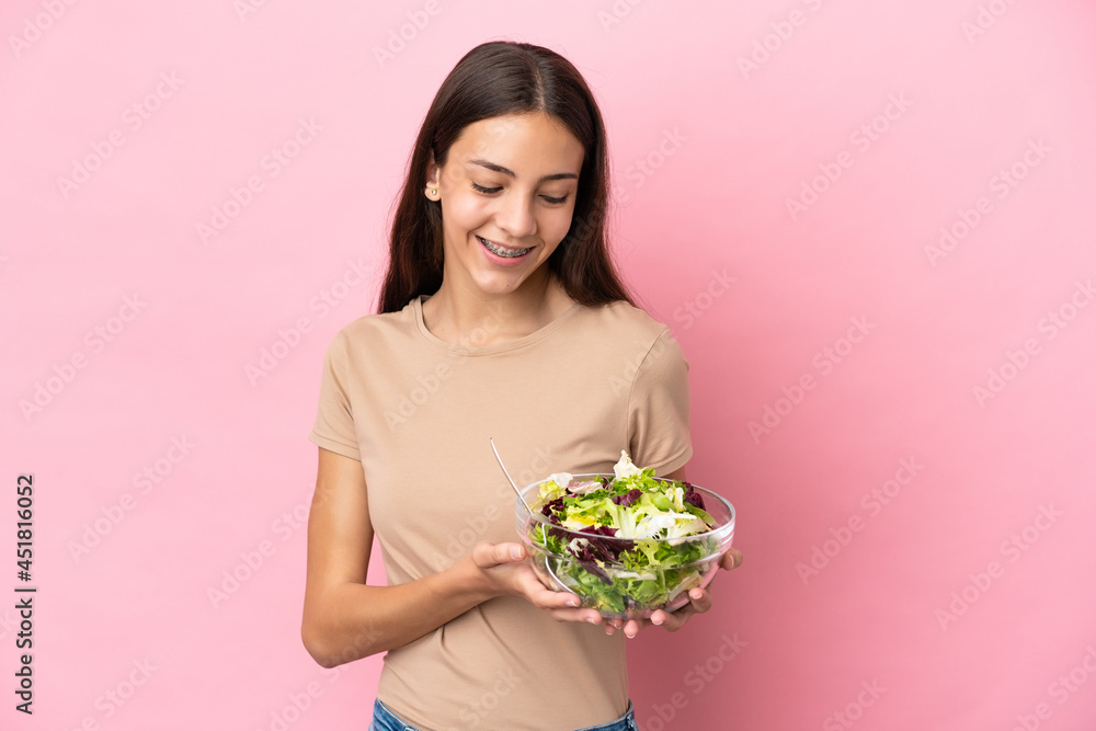 Young French girl isolated on pink background holding a bowl of salad with happy expression Young French girl isolated on pink background holding a bowl of salad with happy expression
