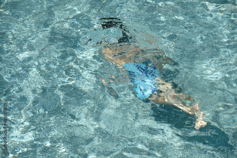 Small boy diving into crystal clear waters of a swimming pool