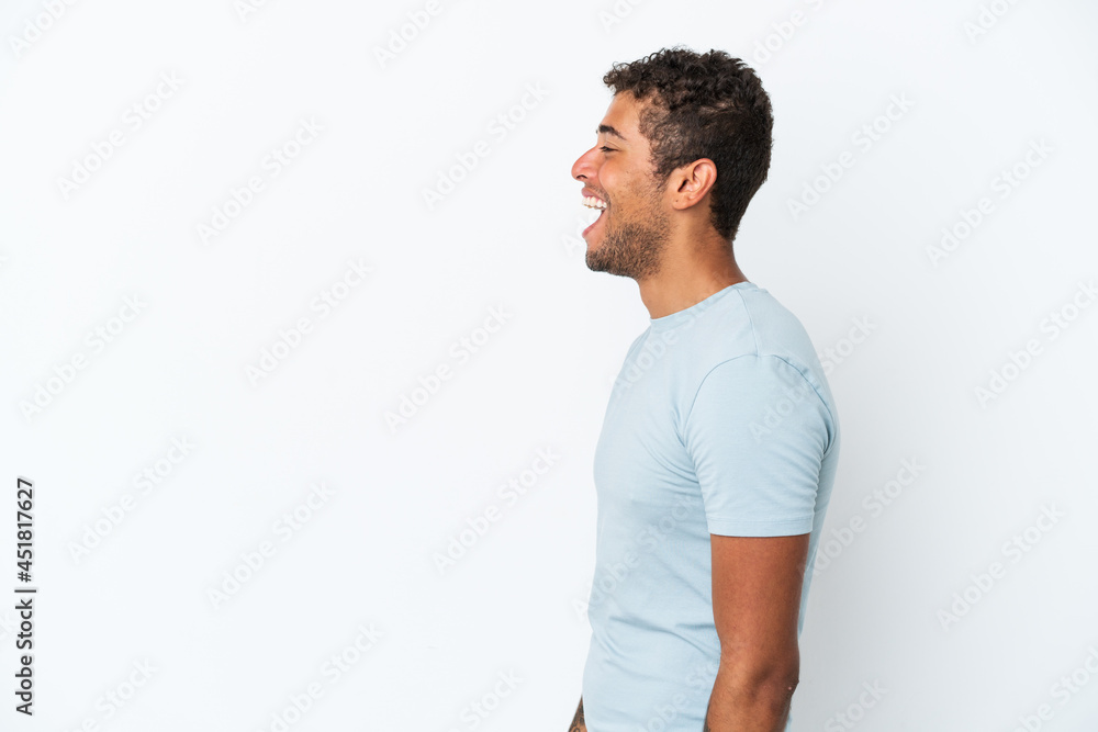 Young handsome Brazilian man isolated on white background laughing in lateral position Young handsome Brazilian man isolated on white background laughing in lateral position