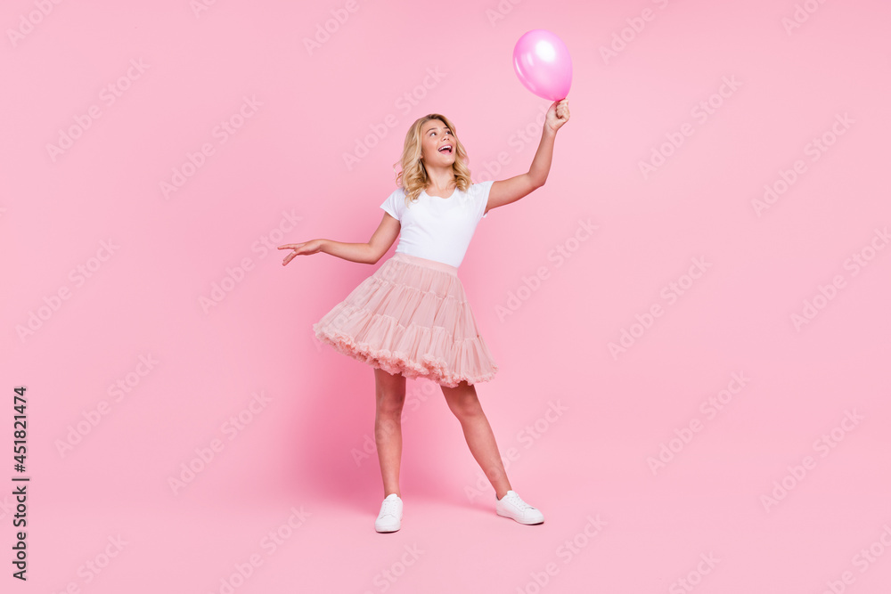 Full length photo of young cheerful girl happy positive smile look air balloon decoration isolated over pink color background Full length photo of young cheerful girl happy positive smile look air balloon decoration isolated over pink color background