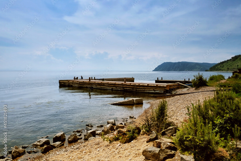 Idyllic view of the wooden pier in the lake with mountain scenery background. Lake Baikal in the day