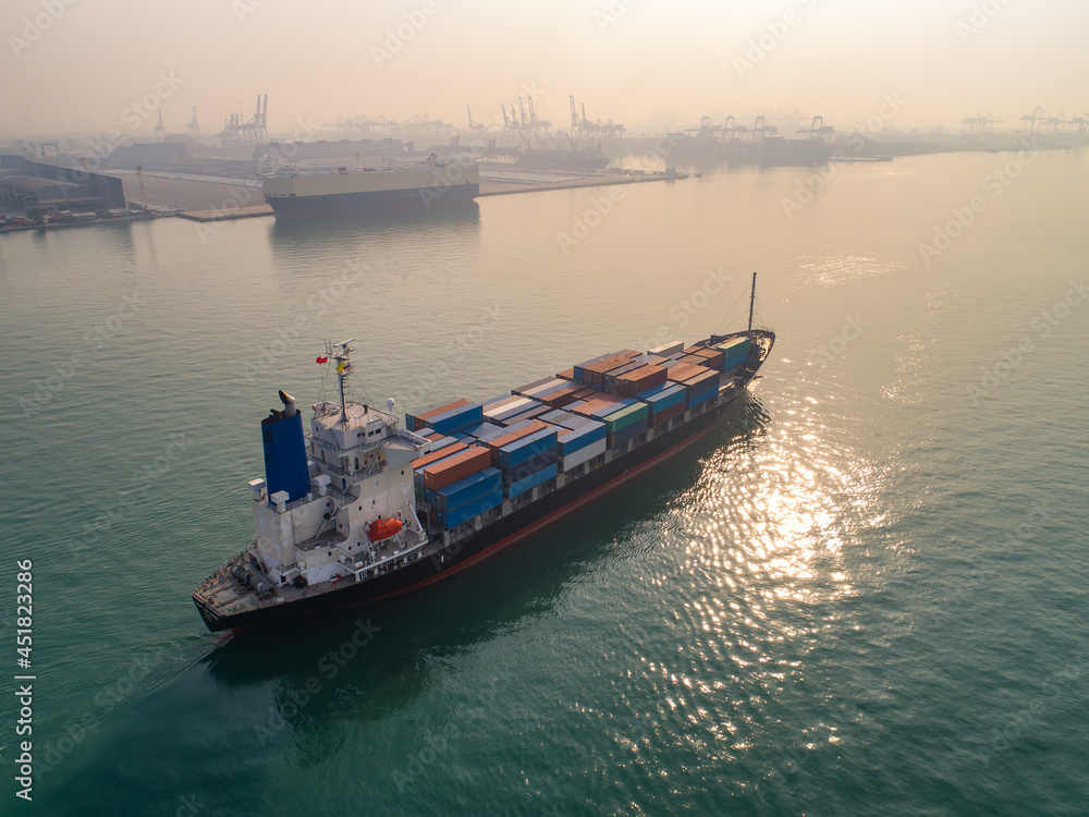 Container ship in export and import business and logistics. Shipping cargo to harbor by crane. Water transport International. Aerial view and top view.
