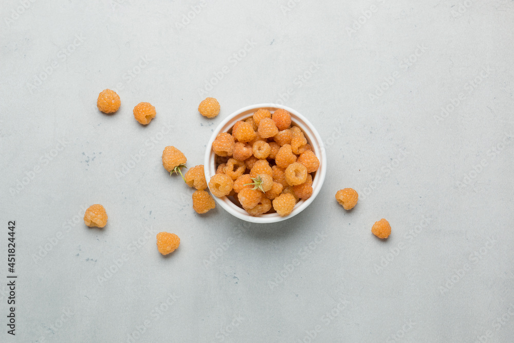 Ripe yellow raspberries. Fresh ripe berry in a white plate on a light background Ripe yellow raspberries. Fresh ripe berry in a white plate on a light background