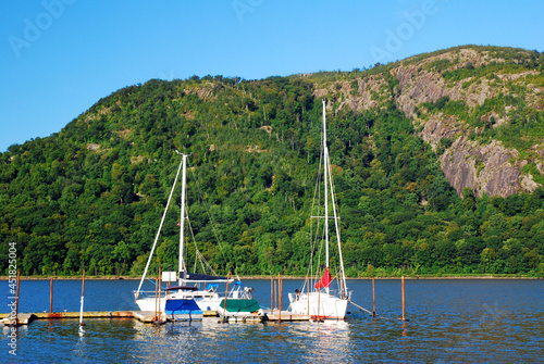 Boats are docked in a small marina surrounded by green hills