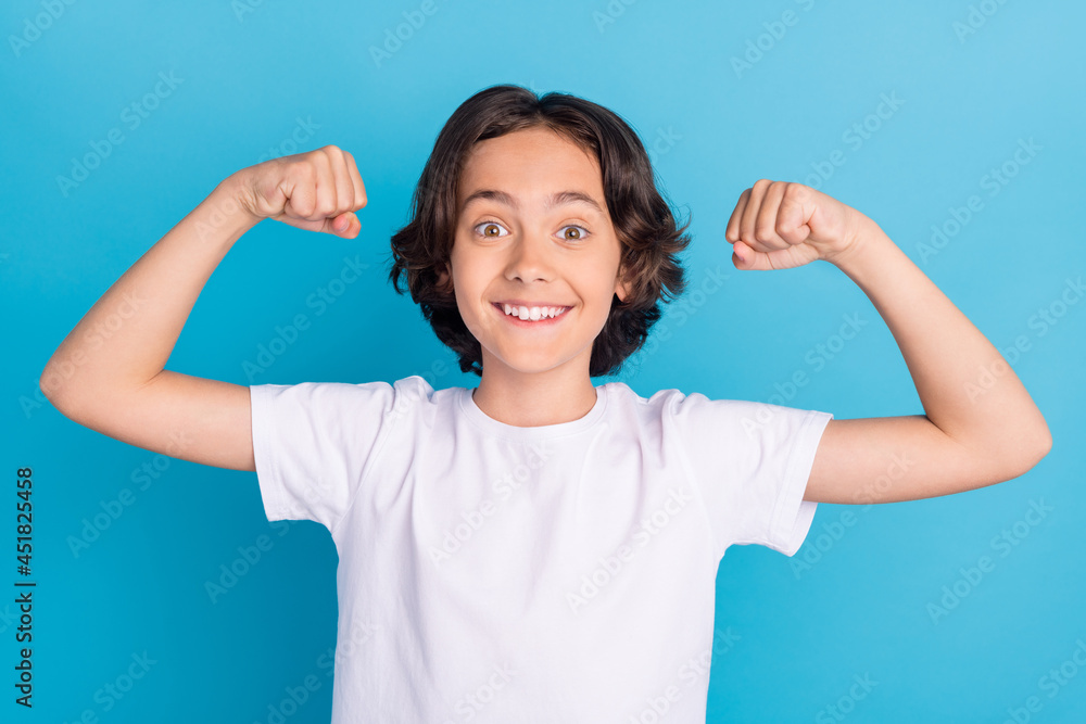 Photo portrait schoolboy smiling showing strong hands isolated pastel blue color background Photo portrait schoolboy smiling showing strong hands isolated pastel blue color background