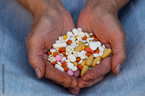 A handful of pills in female hands. A handful of various pills in female hands over light background