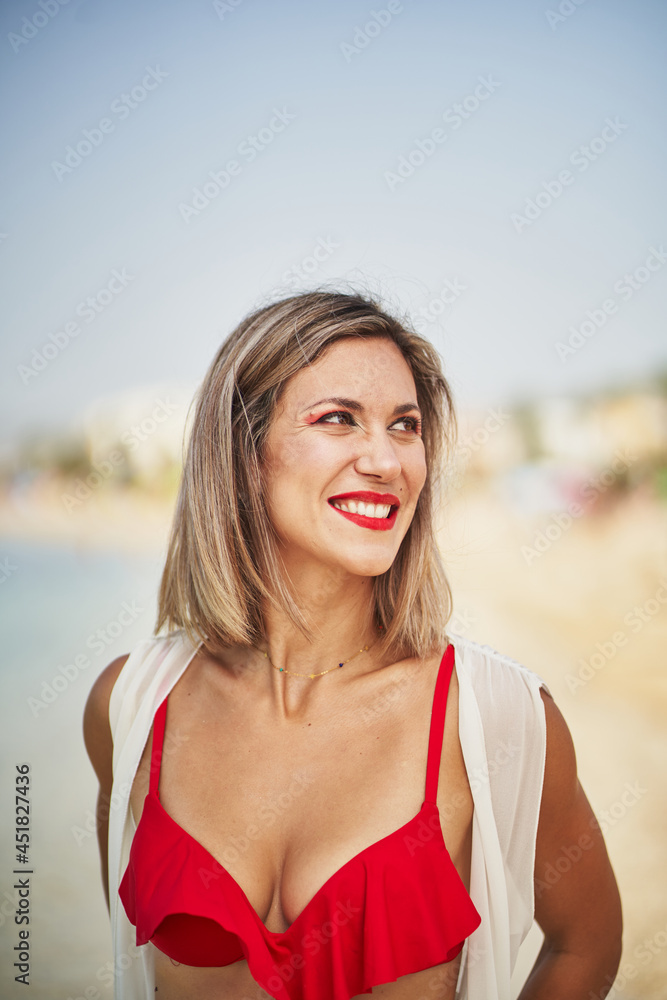 Portrait of hispanic cheerful woman in red bikini smiling in beach