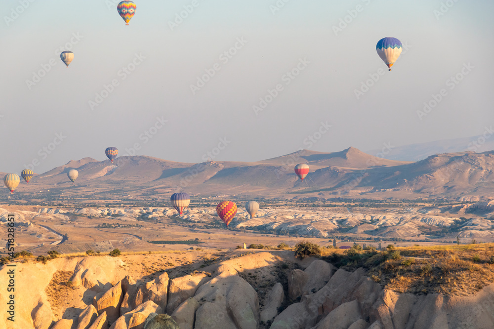 many hot air balloons in the sky over a valley in Cappadocia, Nevsehir, Turkey in a beautiful summer day