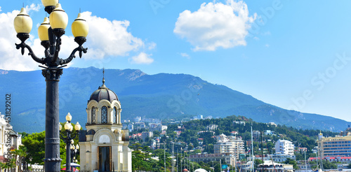 Fotografia Summer view of the Yalta embankment with a church shop, lantern and mountains, Crimea, Yalta, August 2021