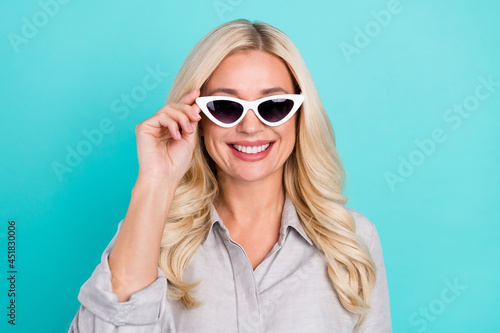 Photo of cheerful traveler lady shiny white smile wear sunglass grey shirt isolated turquoise color background