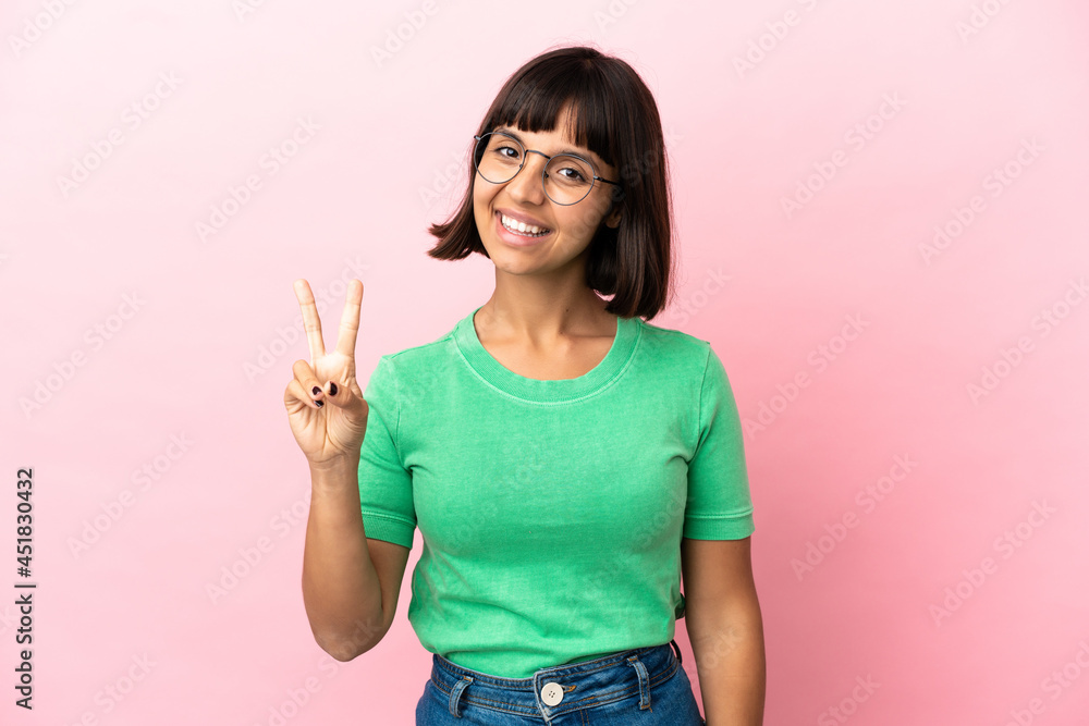 Young mixed race woman isolated on pink background smiling and showing victory sign Young mixed race woman isolated on pink background smiling and showing victory sign