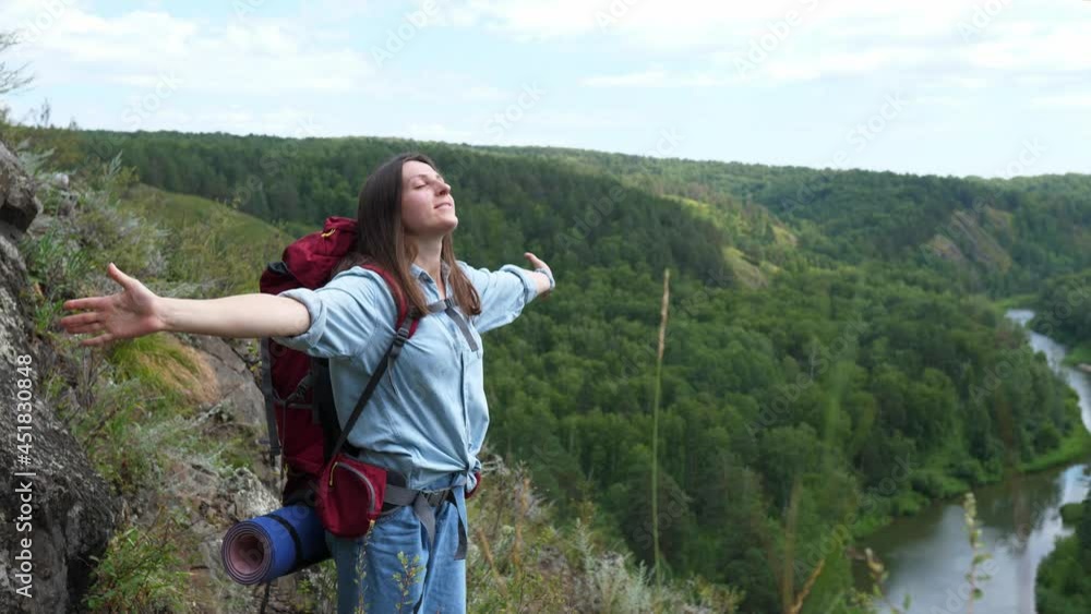 Beautiful young woman, arms spread wide to the sides, enjoys the freedom and the view from the cliff. Beautiful young woman, arms spread wide to the sides, enjoys the freedom and the view from the cliff.