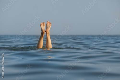 Drowning woman's legs sticking out of sea