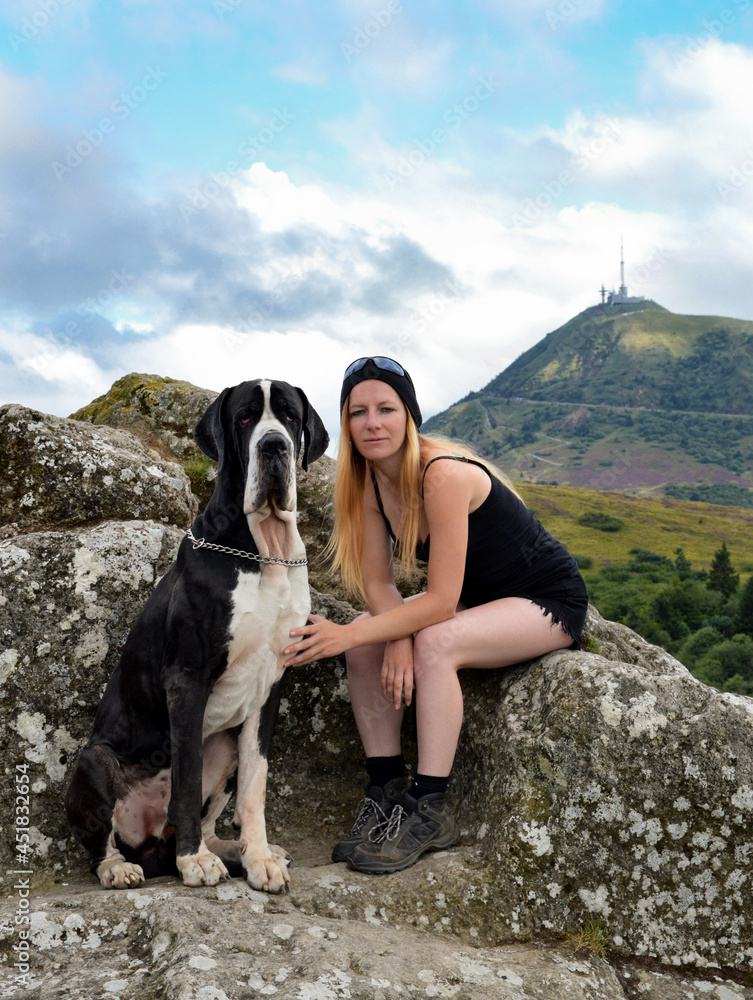 A woman hiker with her dog with a beautiful view on a volcanic mountain.  Puy de Dome volcano in Auvergne.