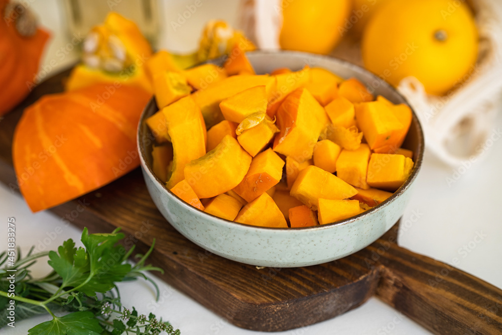 Close up of a plate with raw pumpkin pieces on kitchen table. Positive yellow backgorund. Autumn concept. Thanksgiving day Close up of a plate with raw pumpkin pieces on kitchen table. Positive yellow backgorund. Autumn concept. Thanksgiving day