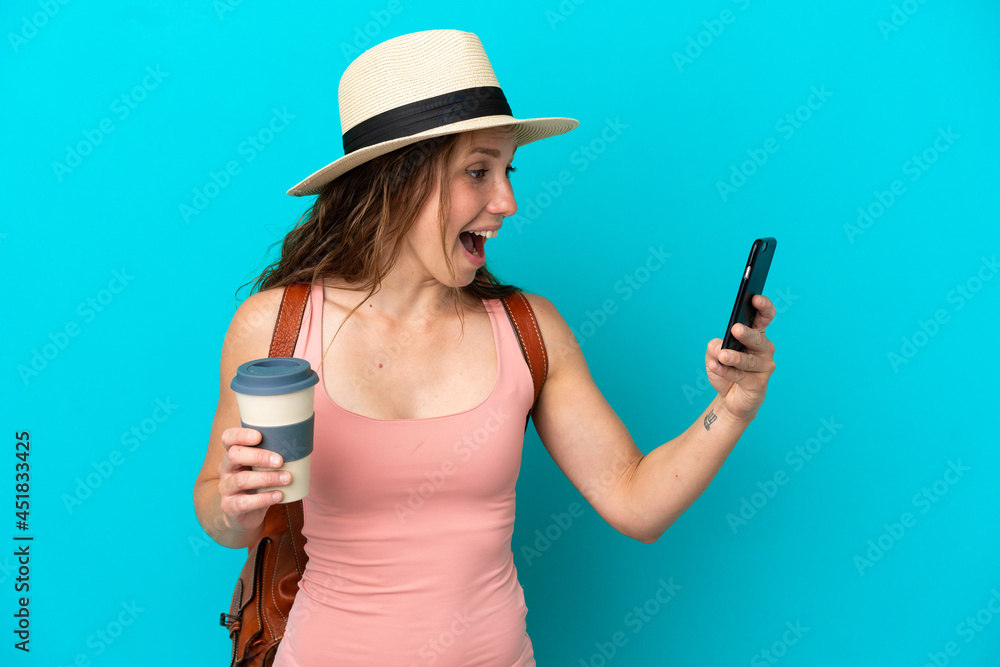 Young caucasian woman in summer holidays isolated on blue background holding coffee to take away and a mobile Young caucasian woman in summer holidays isolated on blue background holding coffee to take away and a mobile