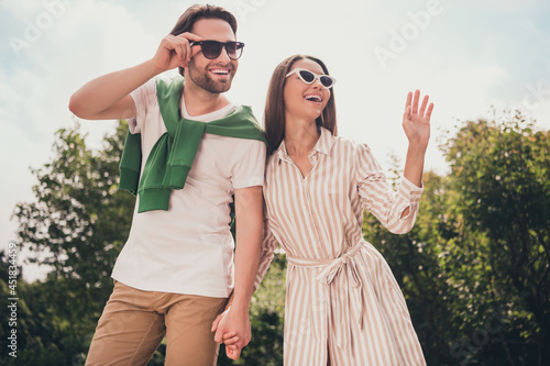 Photo portriat young couple smiling in summer going in park laughing happy waving hands