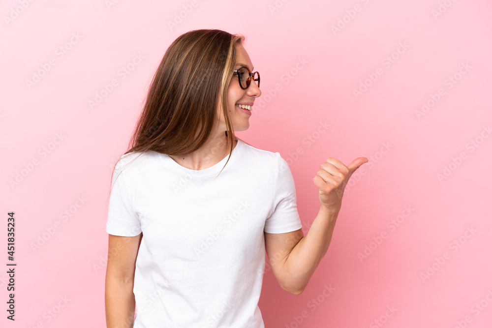 Young English woman isolated on pink background pointing to the side to present a product Young English woman isolated on pink background pointing to the side to present a product