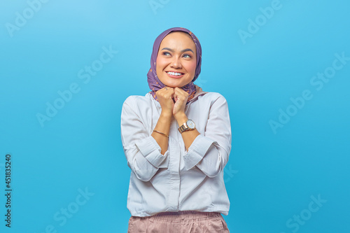 Portrait of dreamy satisfied woman concentrated aside with happy smile, holds hands under chin photo