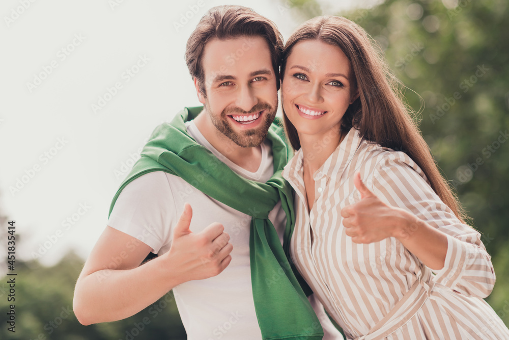 Photo of young cheerful couple happy positive smile hug show thumbs-up like fine feedback ad choose outdoors Photo of young cheerful couple happy positive smile hug show thumbs-up like fine feedback ad choose outdoors