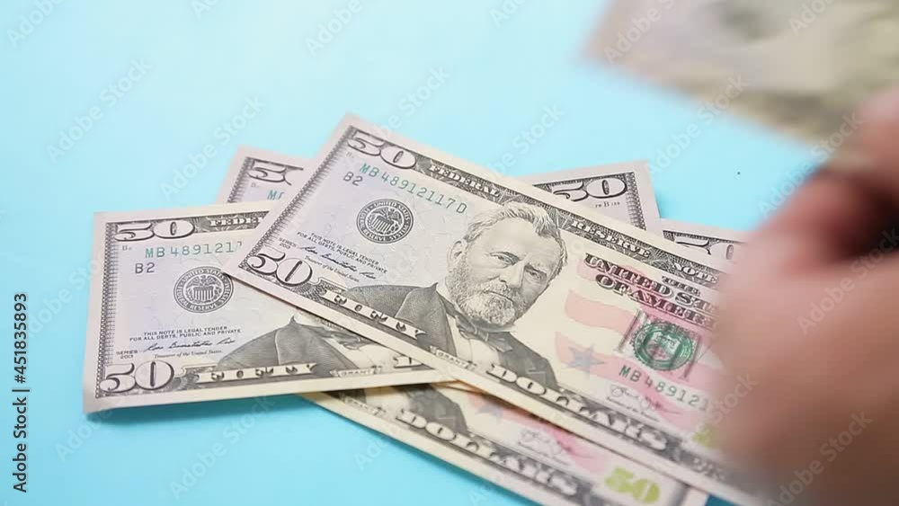 Male hands count dollar bills fifty and one hundred on a blue background Male hands count dollar bills fifty and one hundred on a blue background