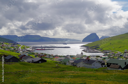 Panoramablick grüne Wiese Bucht auf Färöer Insel Varga mit Felsen Bergen skyline Stadt im Hintergrund - Cliffs and green Grass hills on Faroe Island Varga with rocks and panoramic landscape views	 photo