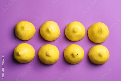 Cut lemons symbolizing women's breasts and one with nipple piercing on purple background, flat lay