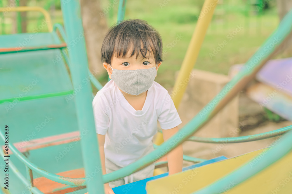 Little boy playing in the playground, the child is wearing a protective mask on the face during the quarantine of coronavirus, covid-19, virus protection. Little boy playing in the playground, the child is wearing a protective mask on the face during the quarantine of coronavirus, covid-19, virus protection.